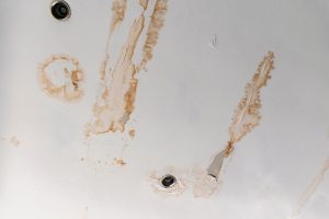 HDB ceiling dripping water with a brown stain ring forming around the wet patch