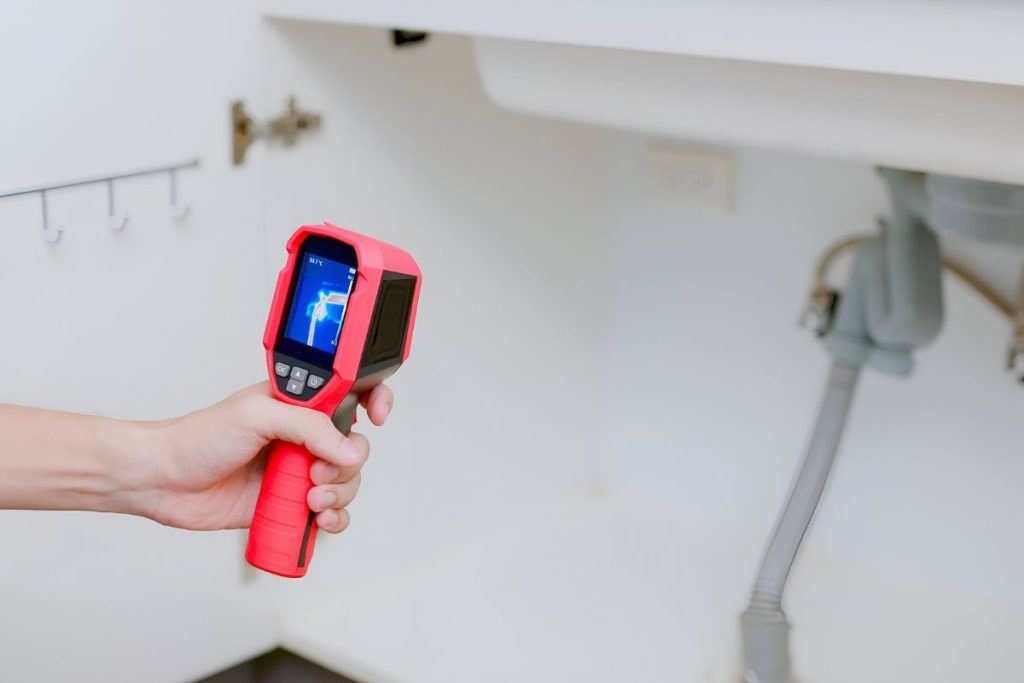 Leak specialist using a moisture meter on a stained condo ceiling during an independent inspection