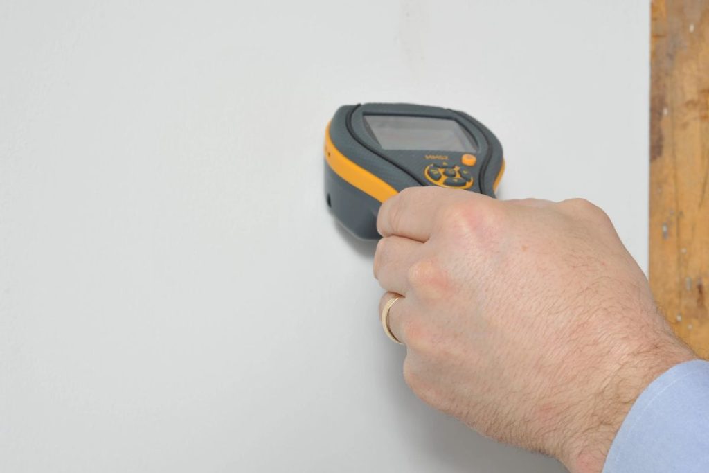 Contractor measuring moisture on a seeping interior wall in Singapore to estimate repair cost
