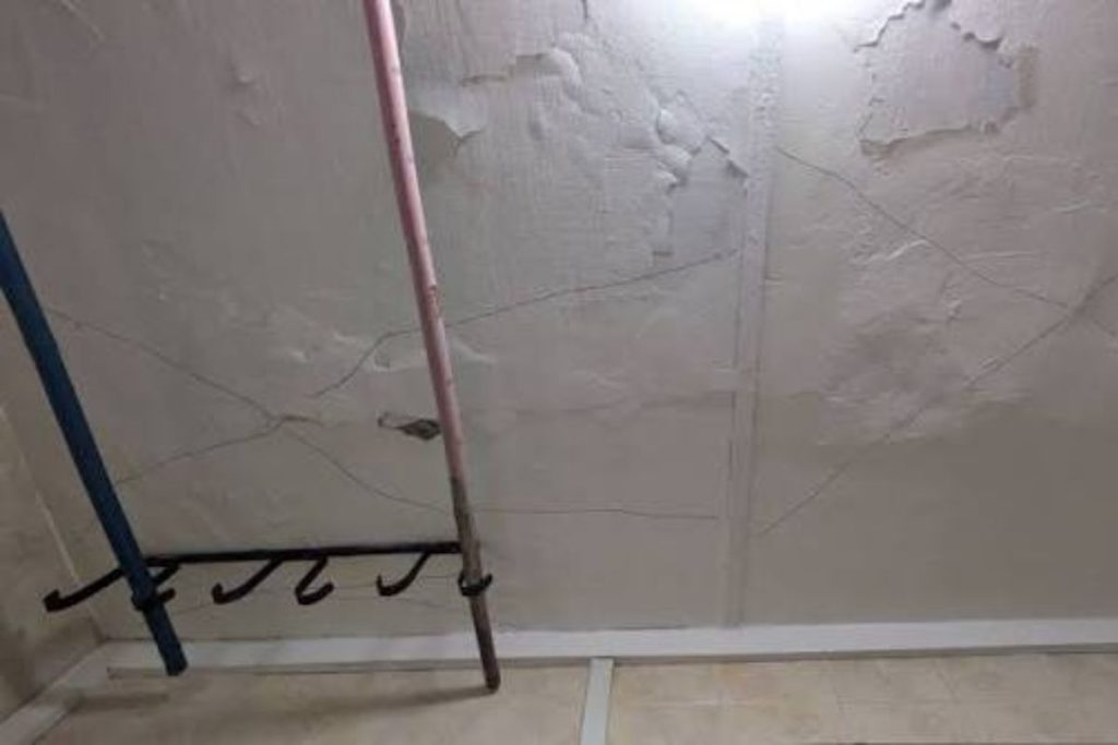 HDB bathroom ceiling spalling with rust stains and cracked concrete around exposed rebar